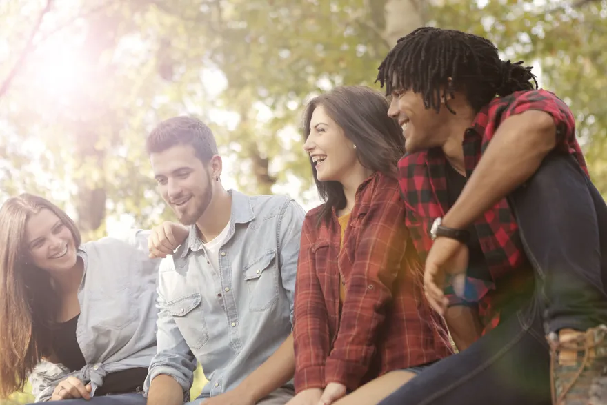 A group of friends laughing together outdoors in the sunshine