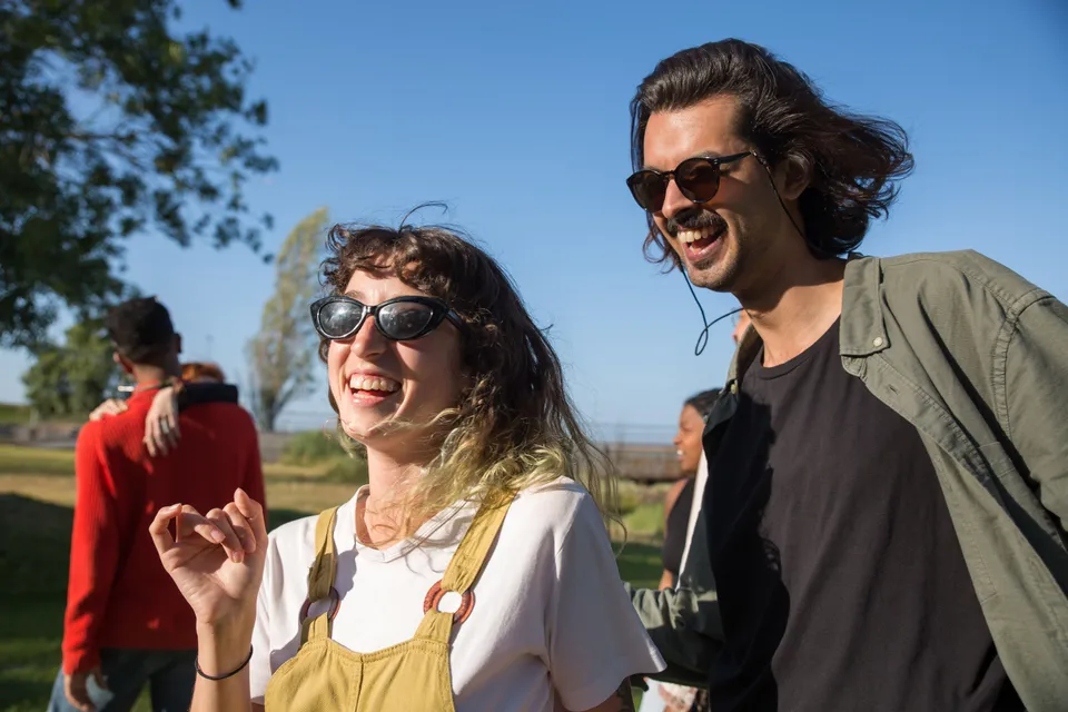 Two friends walking and laughing together outdoors on a sunny day