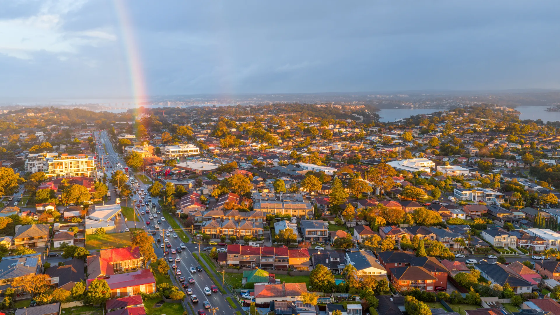 Warm golden light over the tree-lined streets and rooftops of suburban Sydney