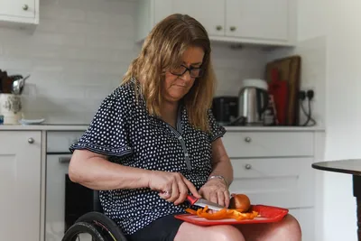 A woman using a wheelchair preparing food independently in a home kitchen