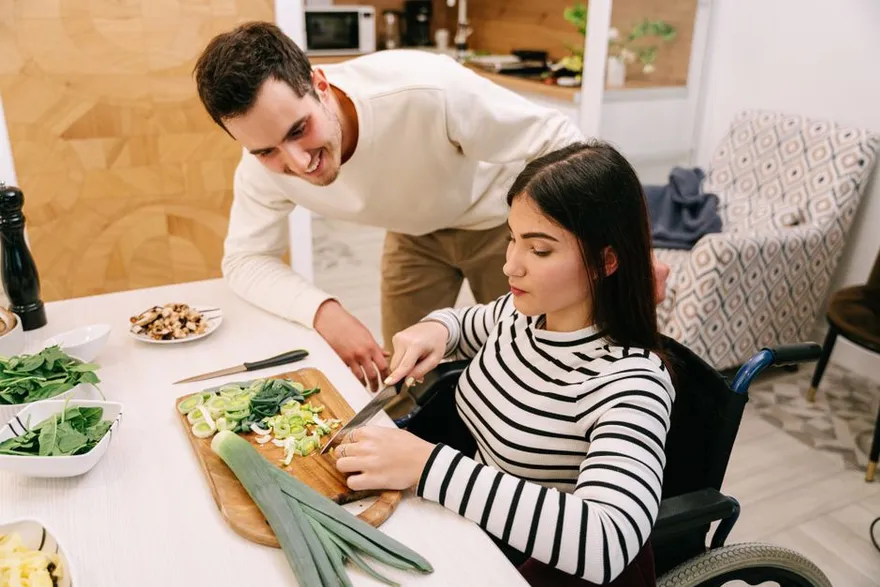 A support worker helping a participant prepare a meal together at home