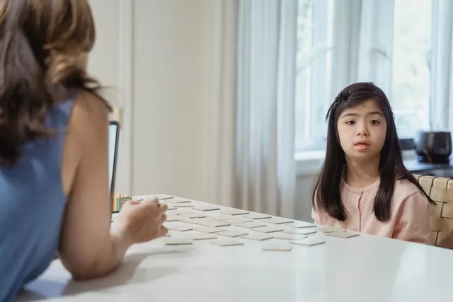A young girl and a woman playing a card game at a table